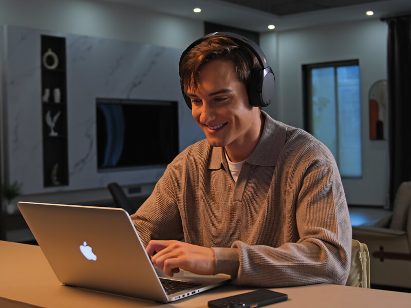 Homme portant le casque Edifier WH950NB devant un MacBook