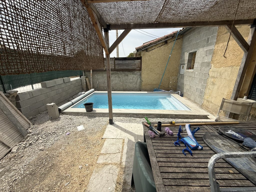 Piscine en eau avec mur de clôture en cours de construction et plage à aménager